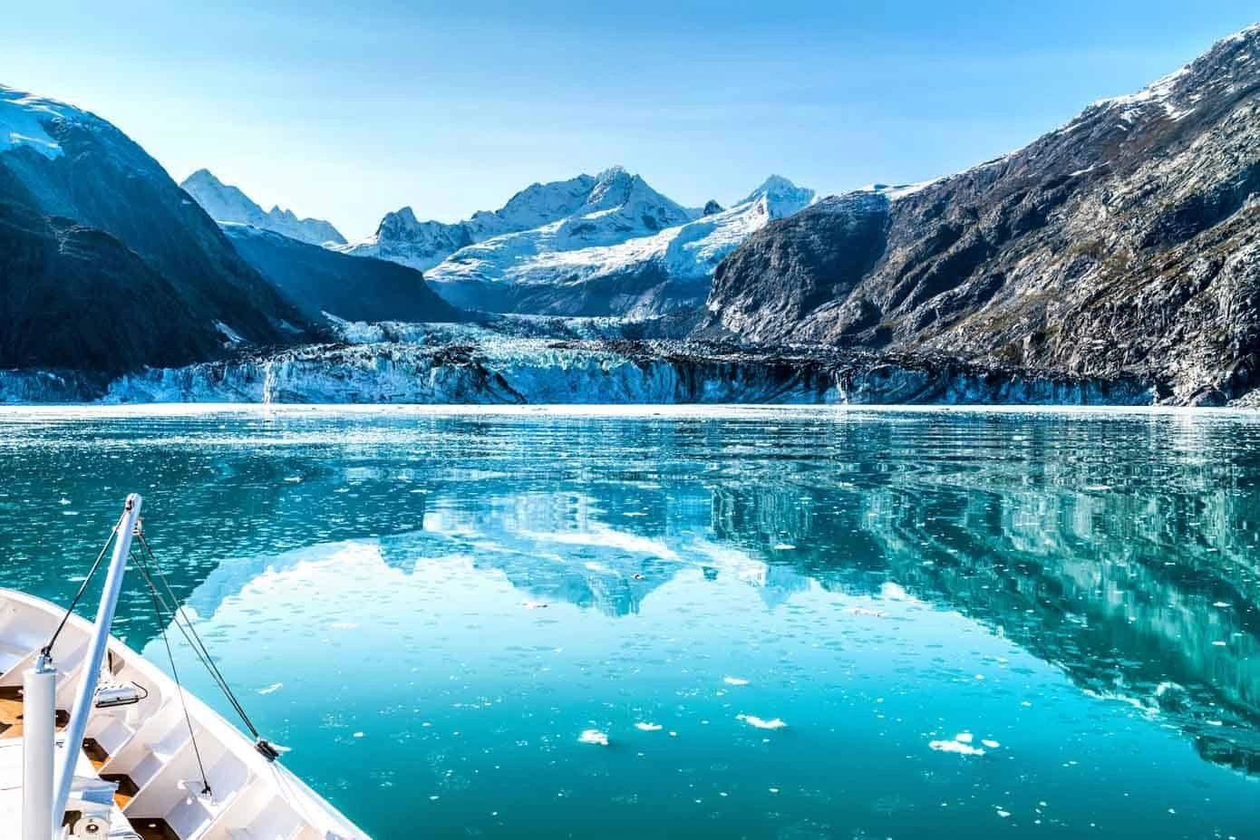 Cruise ship bow approaching a glacier with snow-capped mountains and icy turquoise water